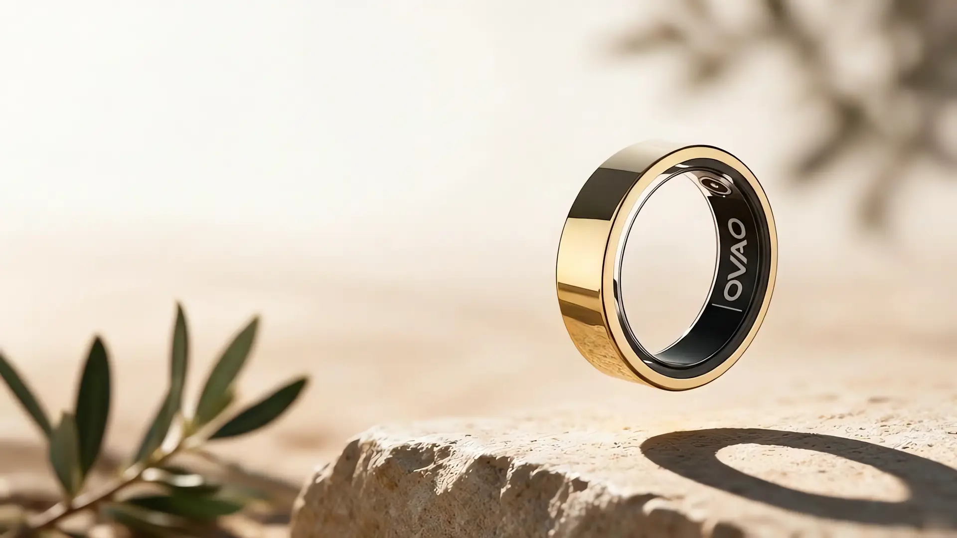 Złoty smart ring OVAO unoszący się nad jasnym kamieniem, ciepłe naturalne światło