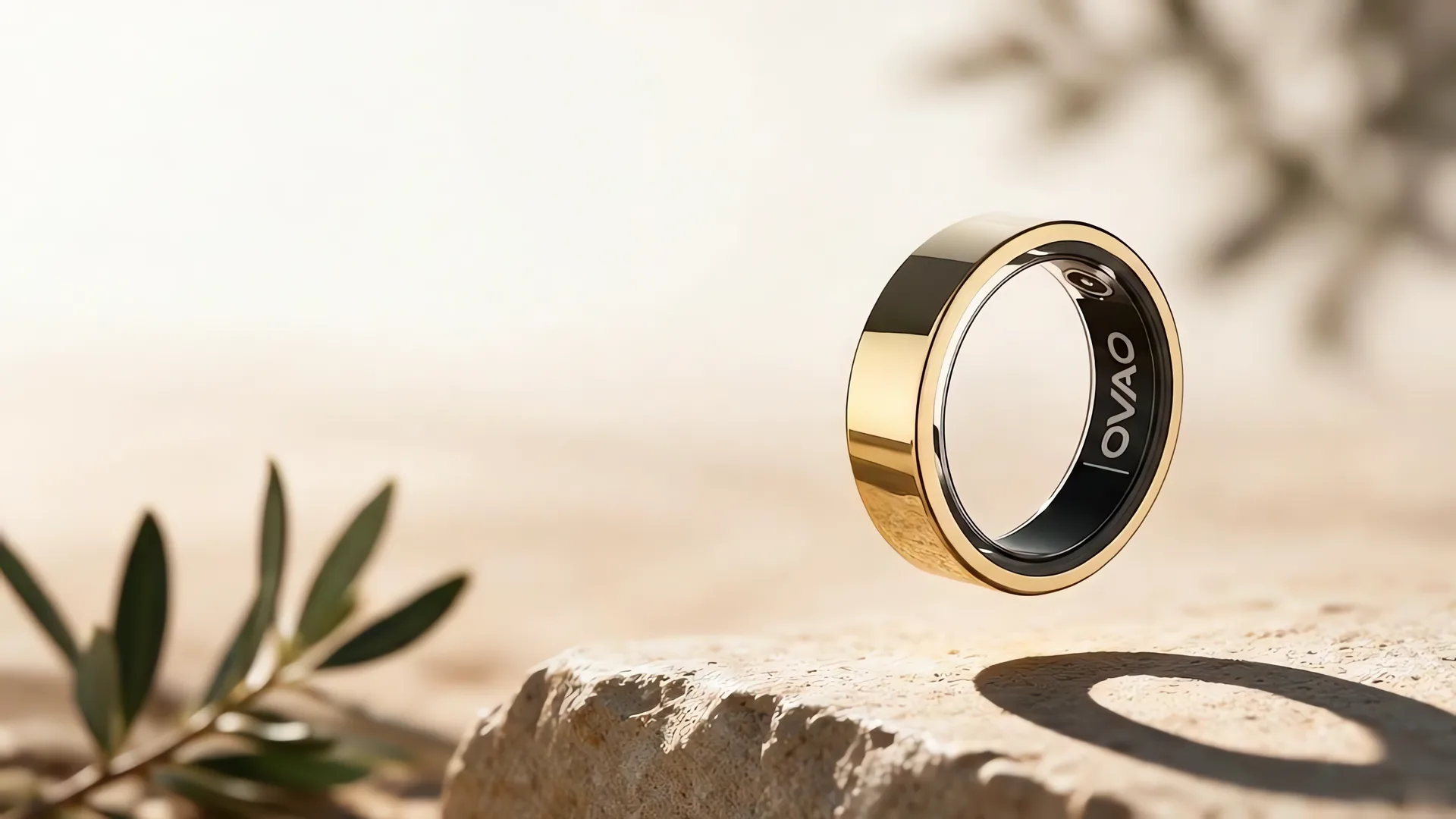 Złoty smart ring OVAO unoszący się nad jasnym kamieniem, ciepłe naturalne światło