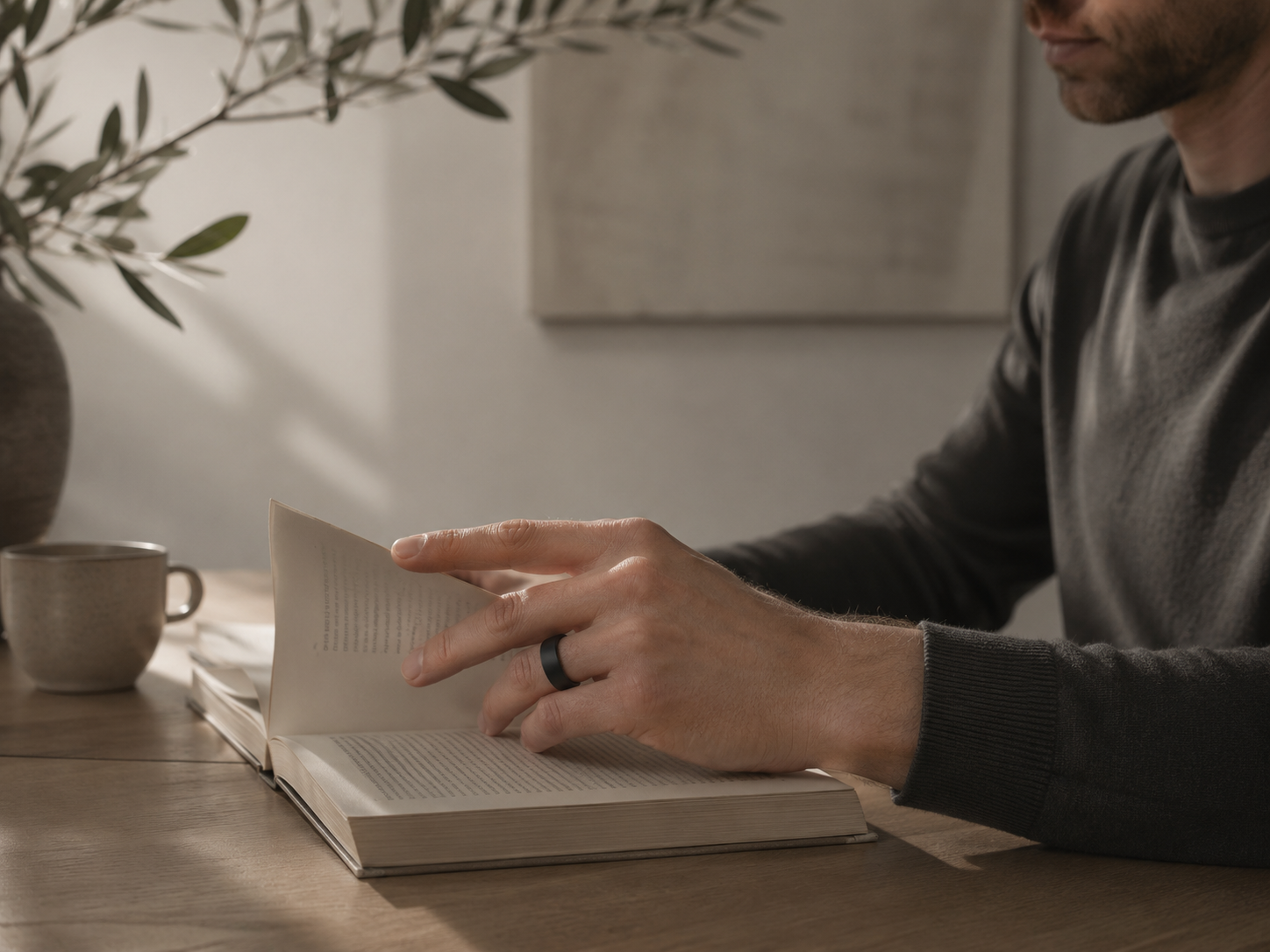 Mężczyzna z książką, smart ring OVAO Onyx na palcu