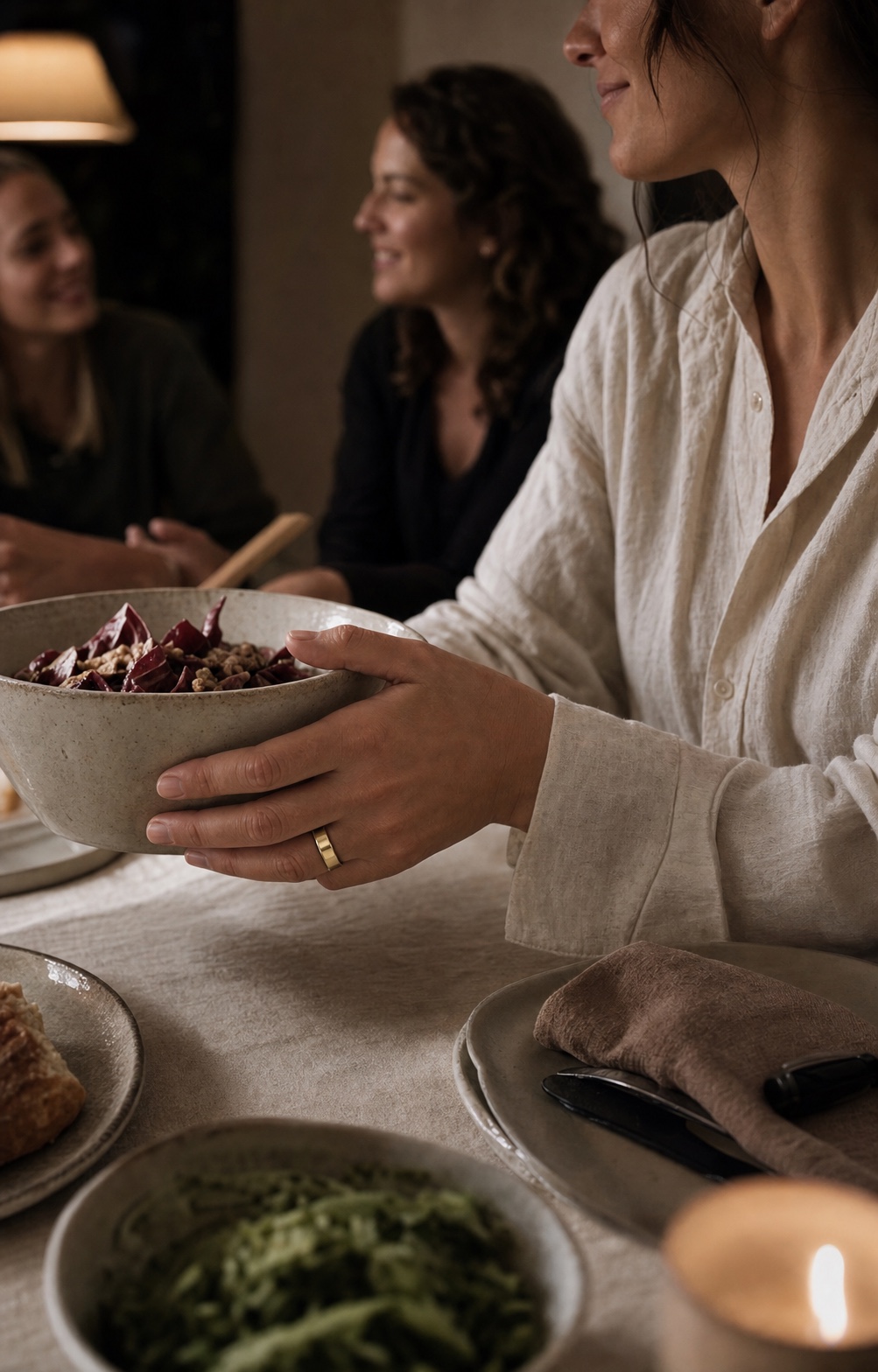 Kobieta podaje ceramiczną misę podczas kolacji z przyjaciółmi, nosi ring OVAO Champagne